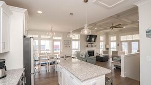 A spacious kitchen with granite countertops, white cabinetry, and pendant lighting.