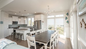 A spacious kitchen with white cabinetry, a central island, and a dining area with a large table and chairs.