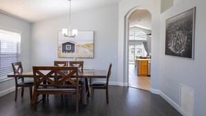 A dining area with a wooden table and chairs, a chandelier, and artwork on the walls.