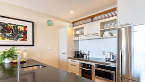 Una cocina moderna con electrodomésticos de acero inoxidable, una encimera negra y armarios blancos.