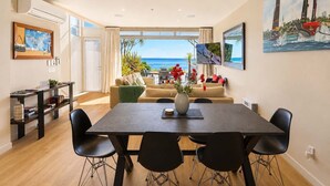 Una sala de estar moderna con comedor, ventanas amplias y vista al mar.
