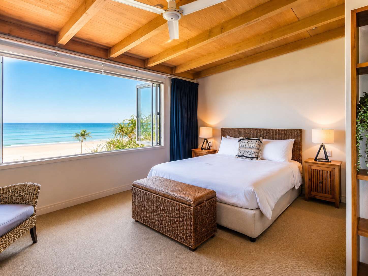 Ein Schlafzimmer mit großem Fenster, einem Bett, einem Nachttisch, einem Sessel und einem kleinen Tisch.