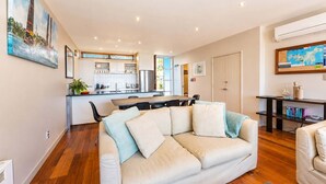 Una sala de estar moderna con un sofá, una zona de comedor y una cocina al fondo.