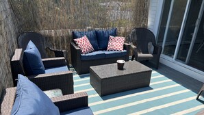 Eine Terrassengruppe im Freien mit Korbmöbeln, darunter Sofas und Sessel, auf einem gestreiften Boden.