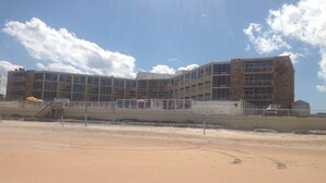 A multi-story hotel with a sandy beach in the foreground.