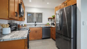 Cocina moderna con armarios de madera, electrodomésticos de acero inoxidable y encimera de granito.