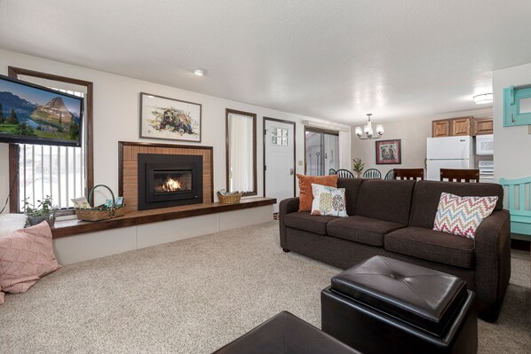 A living room with a fireplace, a sofa, a coffee table, and a dining area with a table and chairs.