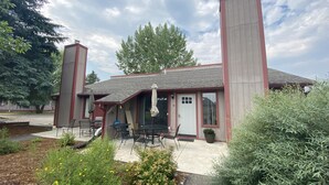 A building with a covered patio area, outdoor seating, and a large chimney.