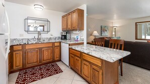 A compact kitchen with wooden cabinets, a built-in dishwasher, and a marble countertop.