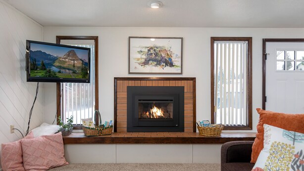 A living room with a fireplace, a mounted TV, and framed artwork on the wall.