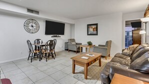 En moderne stue med spiseplads, stort fladskærms-tv og komfortabel sofa.