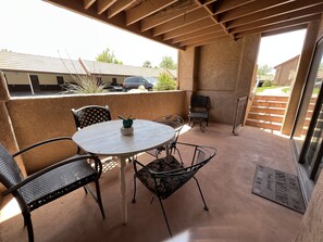 An outdoor patio with a round table and four chairs, a cactus decoration, and a welcome mat. - Red Sands Retreat l Pool & Spa l Pets (St. George)