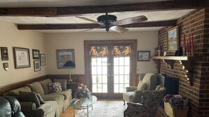 A cozy living room with a fireplace, leather sofas, a coffee table, and a large window with a view. - Beekeeper's House (Buena Vista)