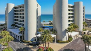 Ein modernes Hotel mit zwei zylindrischen Türmen, einem Pool und Blick auf den Strand.