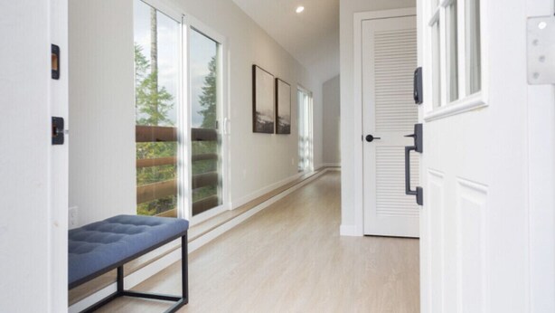A hallway with a bench, sliding glass doors, and framed pictures on the wall. - Stunning Views from this Modern Hood Canal Retreat (Union)