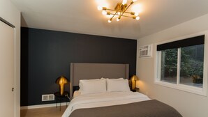A bedroom with a bed, bedside lamps, a window with a view, and a ceiling light fixture. - Stunning Views from this Modern Hood Canal Retreat (Union)