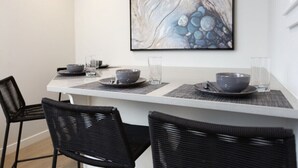 A dining area with a white table, black chairs, and a marble artwork on the wall. - Stunning Views from this Modern Hood Canal Retreat (Union)