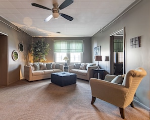 A spacious living room with a ceiling fan, two sofas, a coffee table, and a side chair.