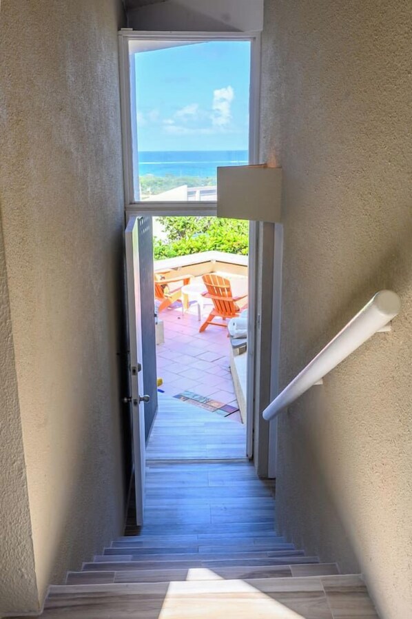 Una escalera conduce a un patio exterior con vista al océano.