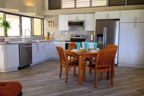 Una cocina moderna con armarios blancos, un refrigerador de acero inoxidable y una mesa de comedor preparada para cuatro comensales.