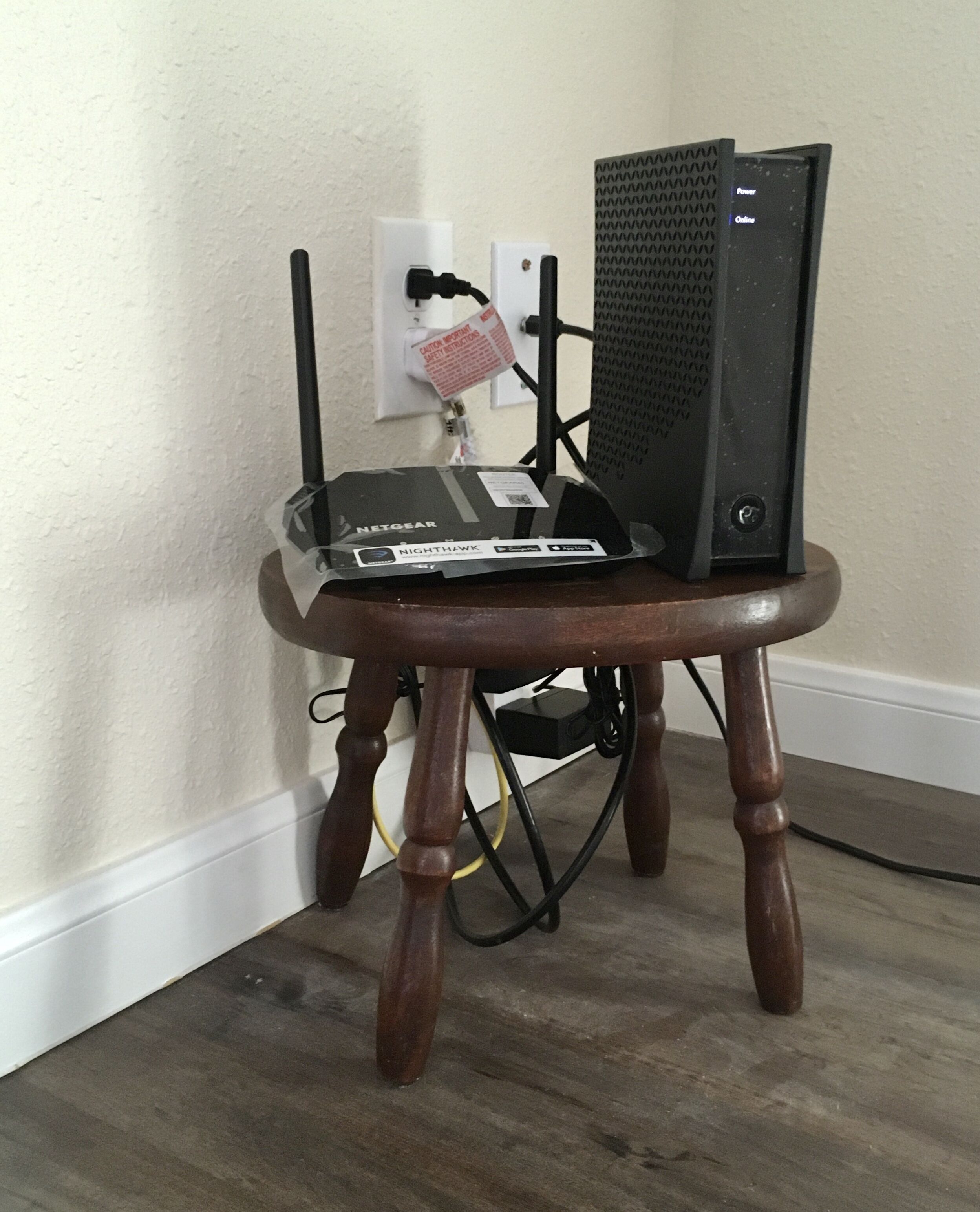 A wooden stool with a black computer and a white device on it.