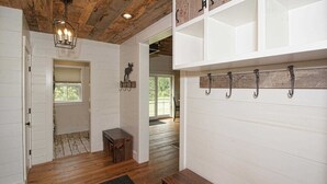 A room with wooden flooring, a bench, a wall-mounted rack with hooks, and a door leading to another room. - Perfect VT getaway - great for two families! Starlink Internet, Large Yard (Stratton)
