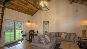 A spacious living room with a wooden ceiling, a sectional sofa, a coffee table, and a dining area with a table and chairs. - Perfect VT getaway - great for two families! Starlink Internet, Large Yard (Stratton)