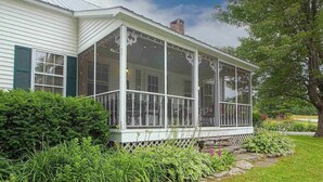 A house with a covered porch, white siding, and green shutters. - Perfect VT getaway - great for two families! Starlink Internet, Large Yard (Stratton)