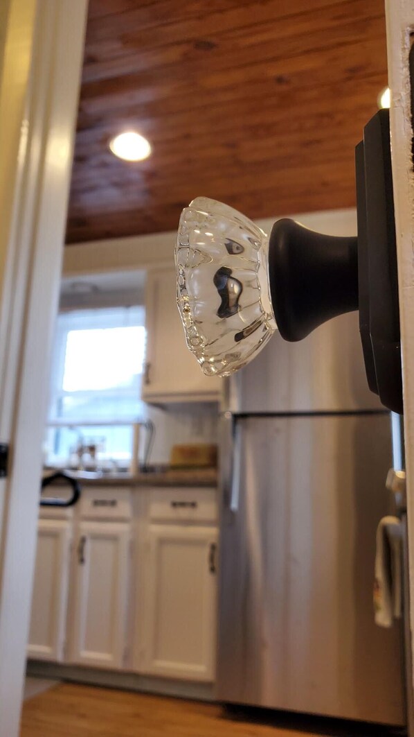 Une cuisine avec des armoires blanches, un réfrigérateur en acier inoxydable et un plafond en bois.