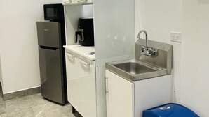 A compact kitchen with white cabinets, a stainless steel sink, a black refrigerator, and a blue trash bin. - 5 Start* New Beautiful Cozy Apart in San Juan P.R (San Juan)