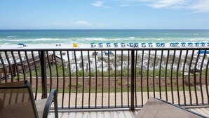 A balcony with a view of the beach, including umbrellas and lounge chairs. - Location Location Location!! (Destin)