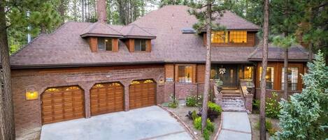 A two-story house with a brick facade, a covered garage, and a well-maintained garden.