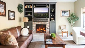 Una sala de estar con chimenea, un sofá, una mesa de centro y un televisor.