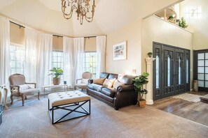 A spacious living room with a leather sofa, a coffee table, and a chandelier.