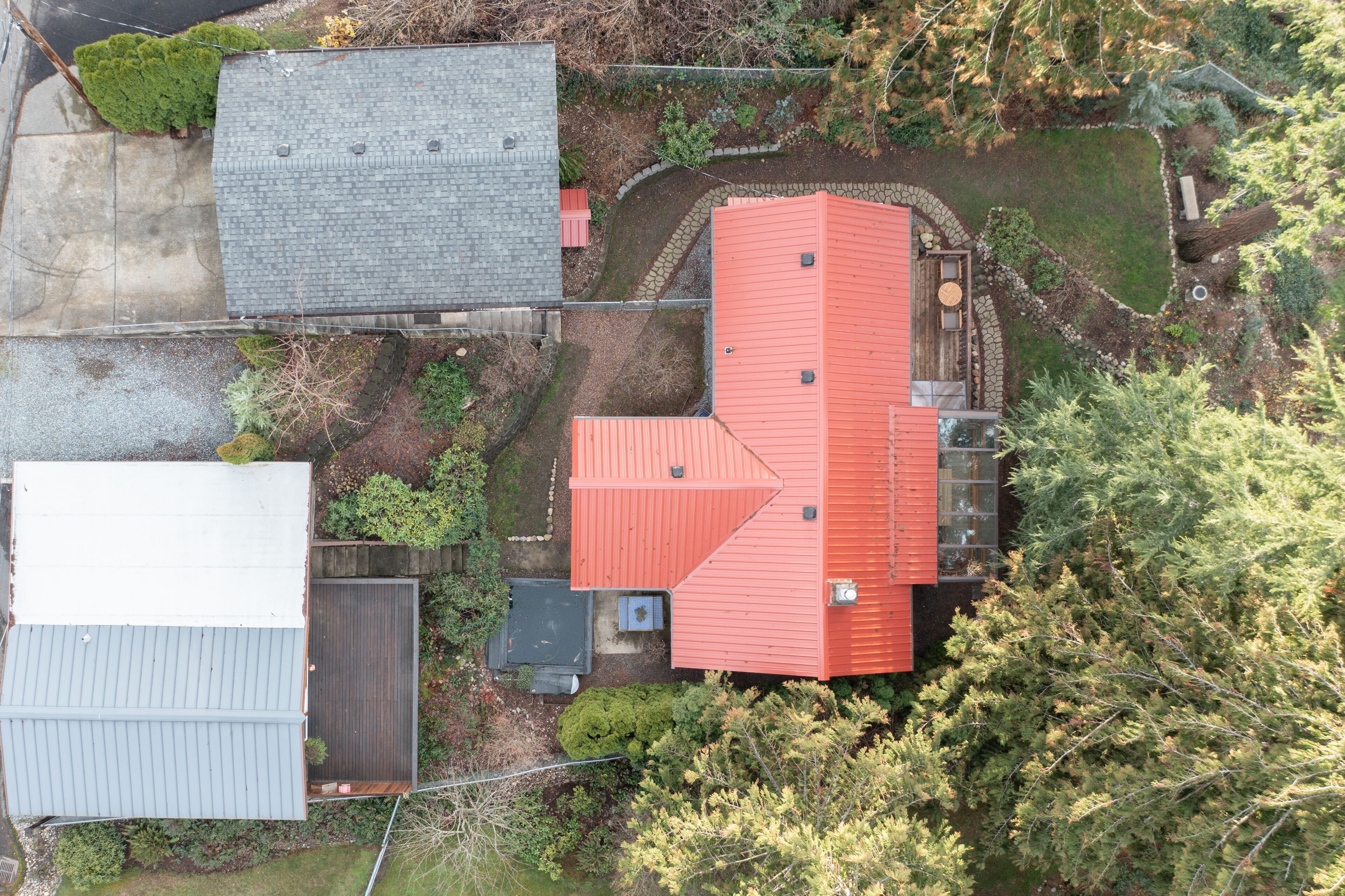 An aerial view of a residential area with multiple houses, including a prominent red-roofed house with a stone foundation and a small porch.