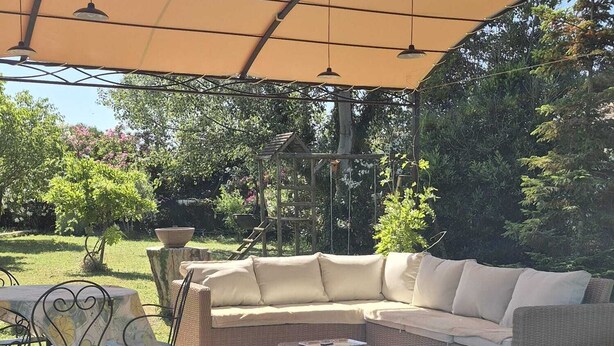 An outdoor patio with a cushioned sofa, a small table, and chairs. - House with pool view (Tulette)