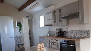 A compact kitchen with a refrigerator, oven, and a dining table with chairs. - House with pool view (Tulette)