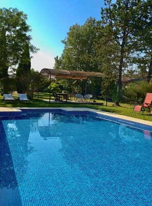 A clear blue pool with tiled edges, surrounded by lounge chairs and a covered seating area. - House with pool view (Tulette)