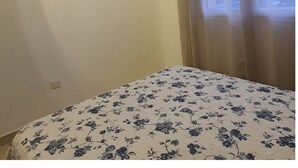 A bedroom with a bed, two wall-mounted paintings, a window with curtains, and a wooden ceiling beam. - House with pool view (Tulette)