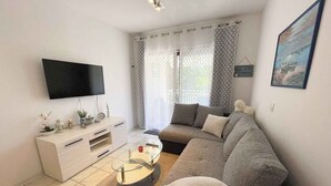 A modern living room with a flat-screen TV, a sofa, a coffee table, and a TV stand. - Holiday apartment modern with balcony (Jadranovo)