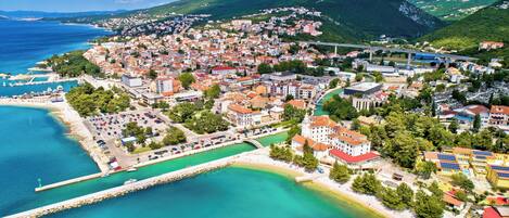 A coastal town with a marina, buildings, and a bridge.