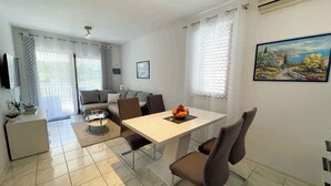 A modern living room with a dining area, a sofa, a TV, and a painting on the wall. - Holiday apartment modern with balcony (Jadranovo)