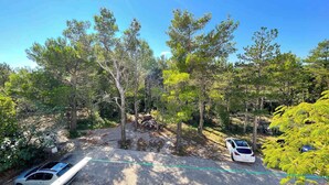 A parking area with two cars, surrounded by trees and a clear sky. - Holiday apartment modern with balcony (Jadranovo)