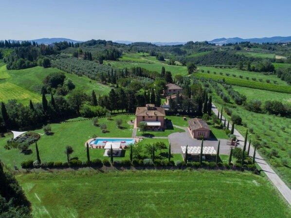 A large estate with multiple buildings, a swimming pool, and expansive green fields.