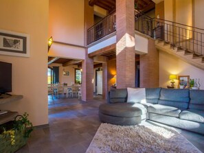 A spacious living area with a large sectional sofa, a fireplace, and a staircase leading to an upper level.