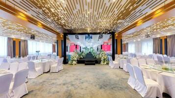Ein Konferenzraum mit runden Tischen und Stühlen, eine Bühne mit Blumendekoration und ein modernes Decken-Design.