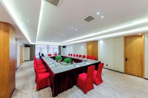 A conference room with a long table, red chairs, and a wooden door. - General Hotel (Longquan)