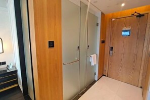 A hotel room with a wooden door, a mirror, and a small window. - General Hotel (Longquan)
