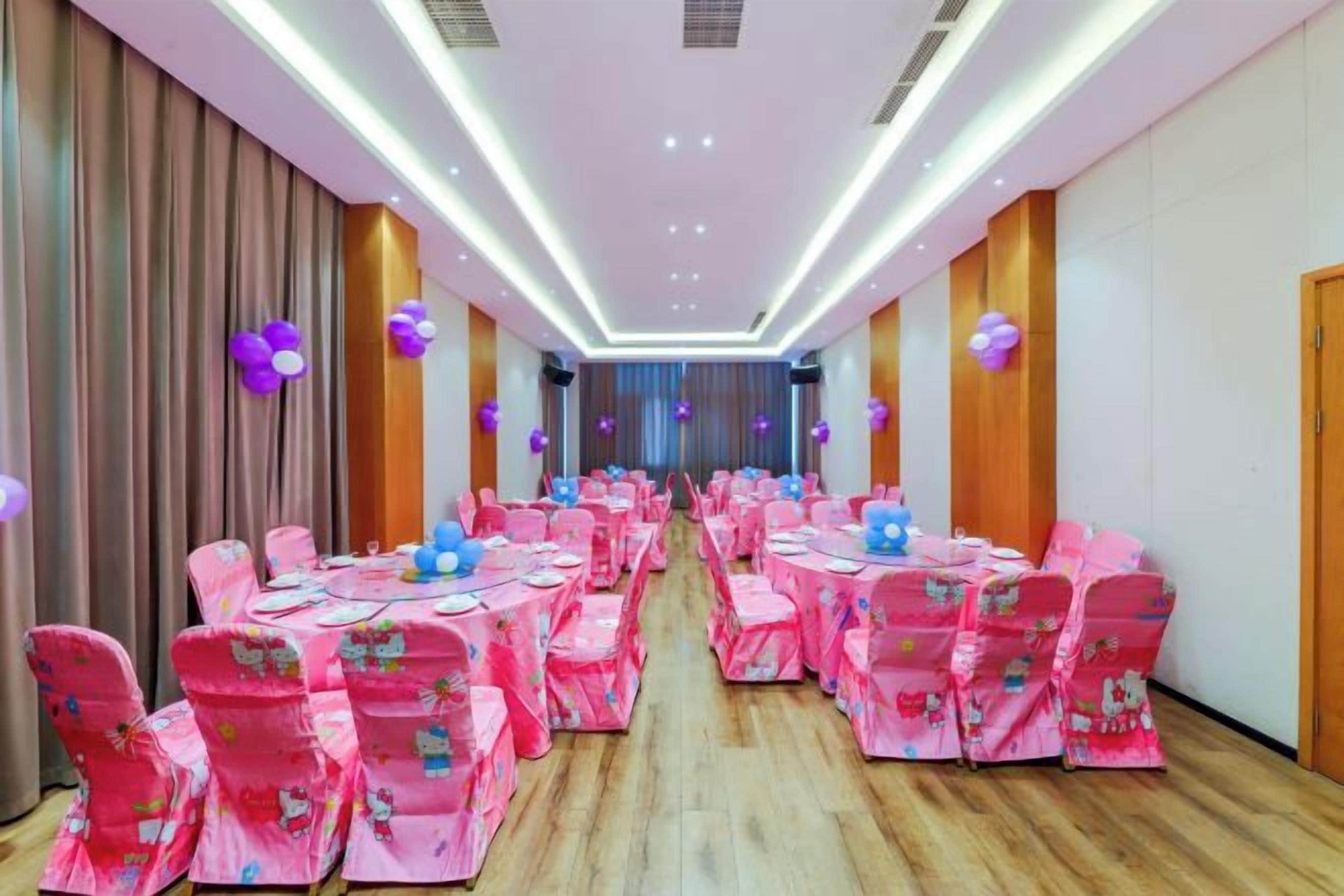 Un salón de banquetes con filas de mesas y sillas, piso de madera y un largo pasillo.