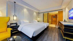 Una habitación de hotel con una cama grande, un sillón amarillo, un escritorio y un televisor.
